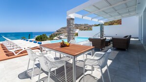 Une terrasse sur le toit avec une piscine, des meubles en osier blancs et une vue sur la mer.