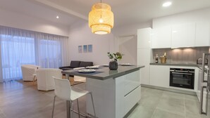 Une cuisine moderne dotée d’un îlot central, de meubles blancs et d’un four encastré.