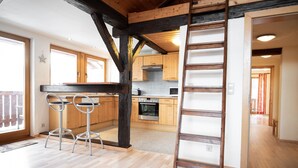 A modern kitchen with wooden cabinets, a central island, and a built-in oven. - Lake View Lodges - Penthouse (Zell am See)
