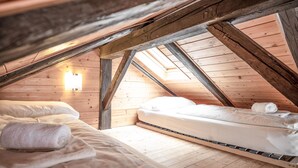 A cozy attic bedroom with wooden beams, a skylight, and two beds with neatly made linens. - Lake View Lodges - Penthouse (Zell am See)
