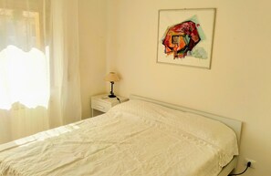 A bedroom with a bed, a nightstand, a lamp, and a painting on the wall. - Piazza Del Grano Treviso (Treviso)