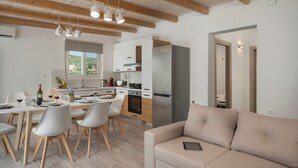 A modern kitchen with white cabinets, a stainless steel refrigerator, and wooden beams on the ceiling. - B&M Villa Sirili (Platanias)