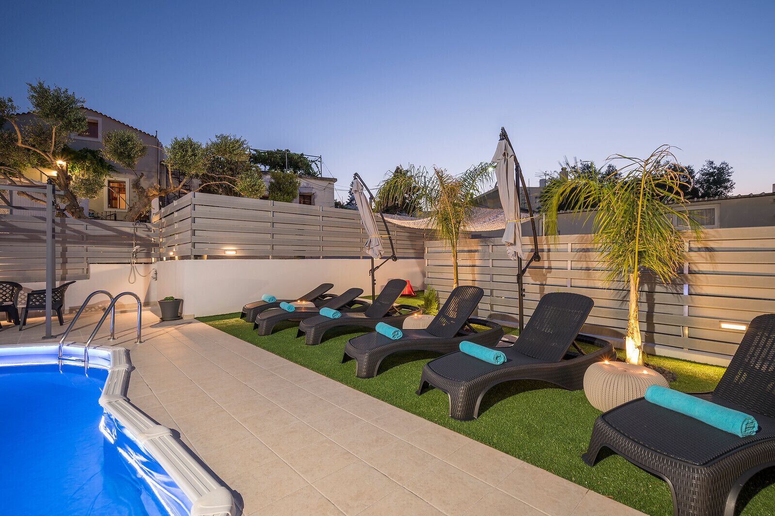 Un área junto a la piscina con sillones de descanso y una piscina pequeña.