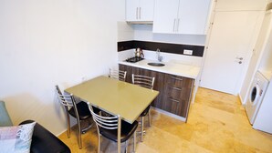 Une cuisine compacte comprenant une table à manger, des chaises, un évier et un lave-linge.