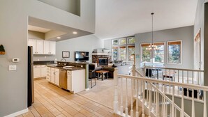 A spacious kitchen with a dining area, a living room, and a staircase leading to an upper level.