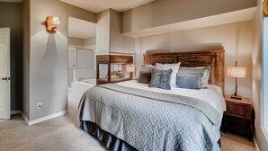 A bedroom with a large bed, bedside lamps, a nightstand, and a mirror.