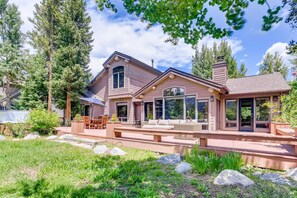 A two-story house with a patio, outdoor seating, and a large window overlooking the yard.