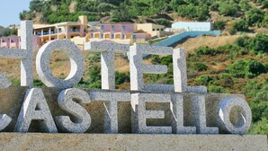 Un letrero de piedra con las palabras 'HOTEL CASTELLO' en letras grandes.