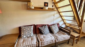 Ein gemütliches Zimmer mit einer Holzbank, gepolsterten Sitzgelegenheiten, einer Holztreppe und einem Regal mit Dekorationsobjekten.