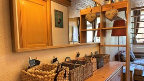 Ein Holztresen mit gewebten Körben und einem Spiegel, der einen Raum mit einem Bett und einem Fenster reflektiert.