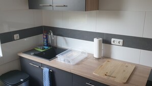 A modern kitchen with a sink, countertop, and a cutting board. - Privatzimmer EKO 1 (Kassel)
