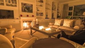 A cozy living room with a fireplace, comfortable seating, and a bookshelf. - 18 On Hillwood Villa (Bishopscourt)