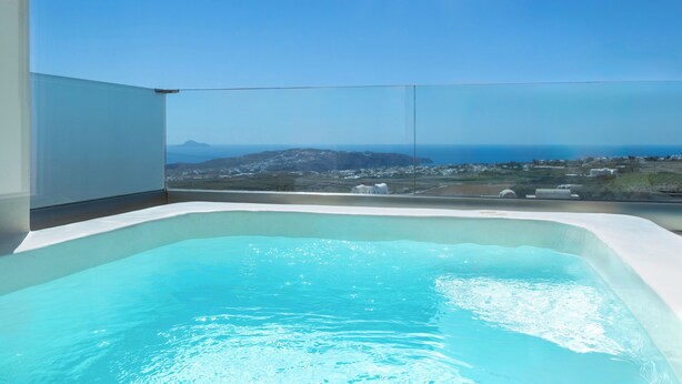 A modern indoor swimming pool with a clear view of the ocean and distant landscape. - Cinnamon Villa with Private Hot Tub (Santorini)