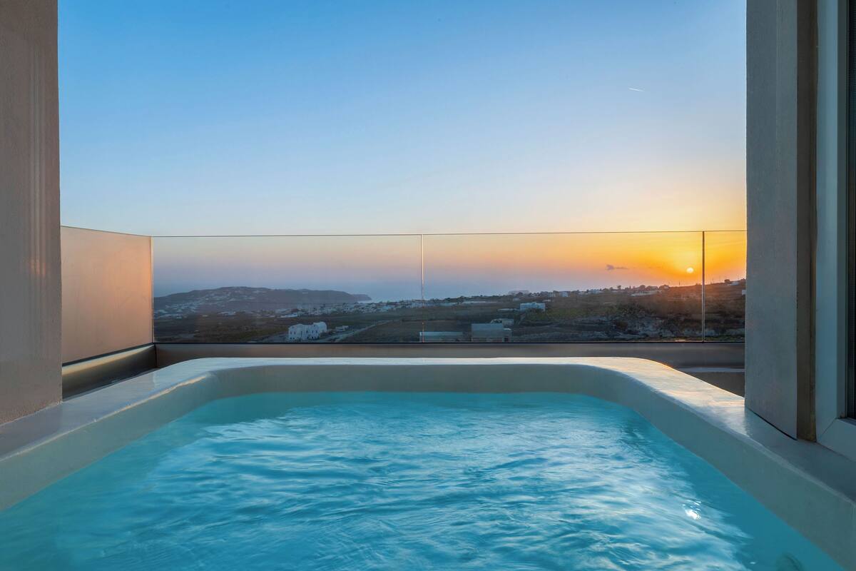 A hot tub with a view of a sunset over a landscape.