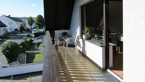 A balcony with a view of parked cars and houses, a potted plant, and a table with chairs. - AhrHeim Brave new apartment on the Ahr (Bad Neuenahr)