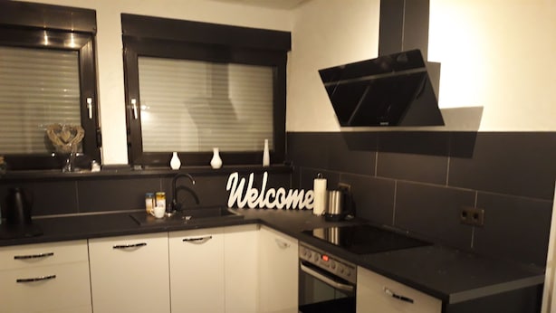 A modern kitchen with black countertops, white cabinets, a built-in oven, and a microwave. - AhrHeim Brave new apartment on the Ahr (Bad Neuenahr)