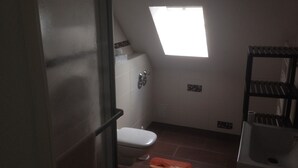 Une petite salle de bain compacte, équipée de toilettes, d’un lavabo et d’une fenêtre.