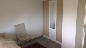 Une chambre à coucher avec un lit, une chaise, une armoire et un miroir.