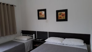Une chambre d’hôtel avec deux lits simples, une table de chevet et deux tableaux représentant des motifs floraux, encadrés et accrochés au mur.