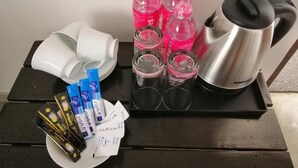 Una bandeja con una cafetera, botellas rosas, vasos y paquetes de comida.