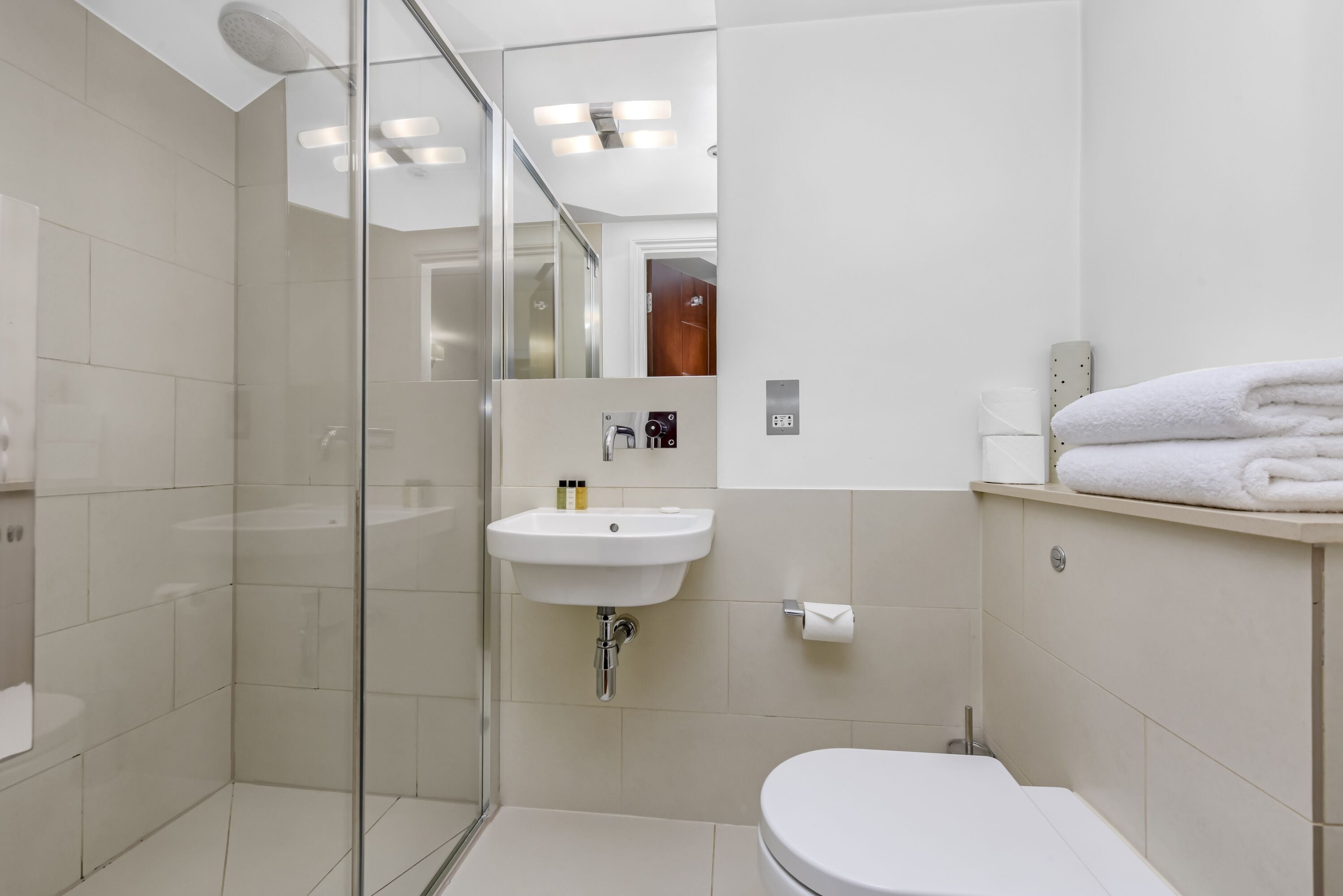 A modern bathroom with a glass shower enclosure, a white sink, and a toilet.