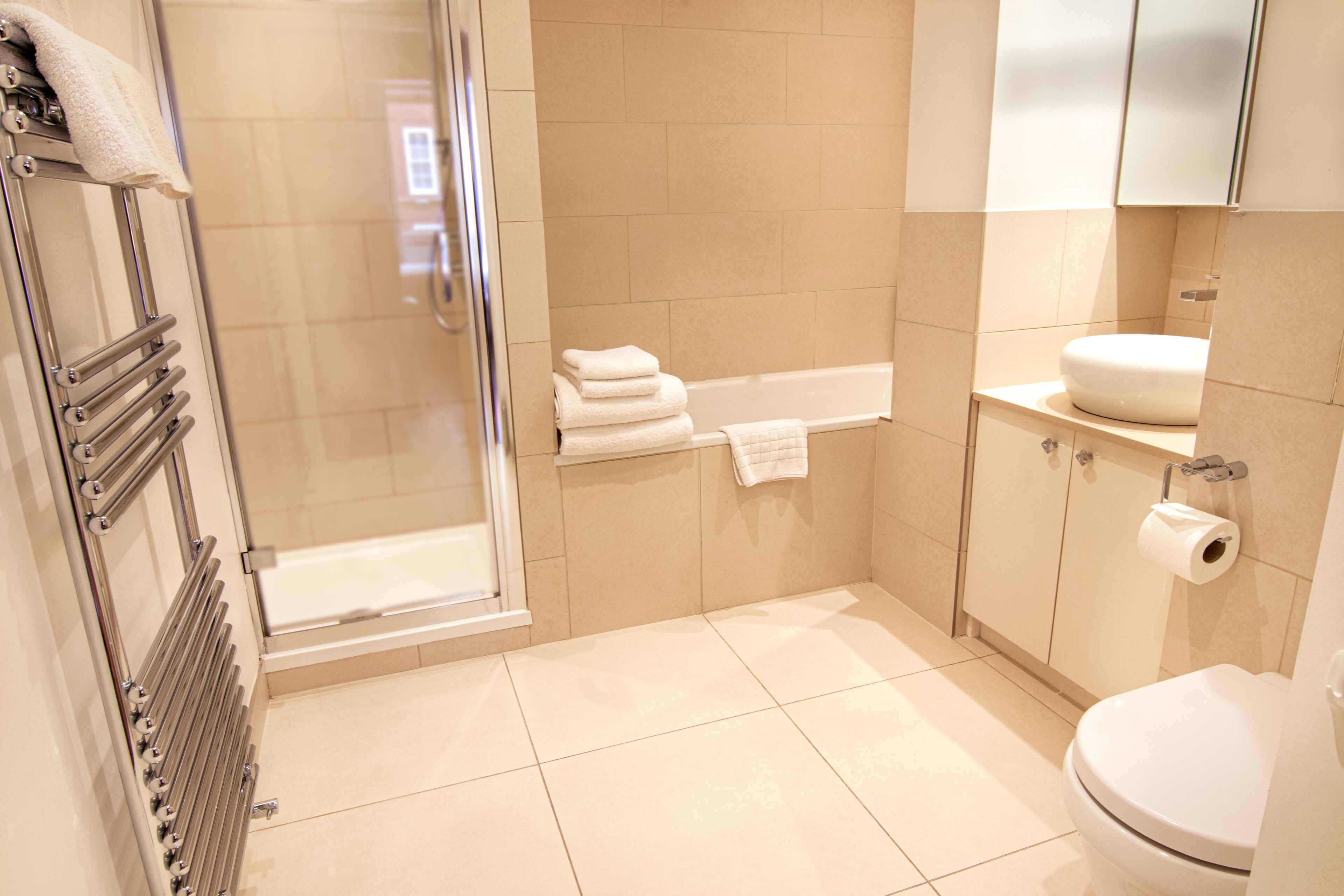 A modern bathroom with a glass shower enclosure, a bathtub, a toilet, and a sink.