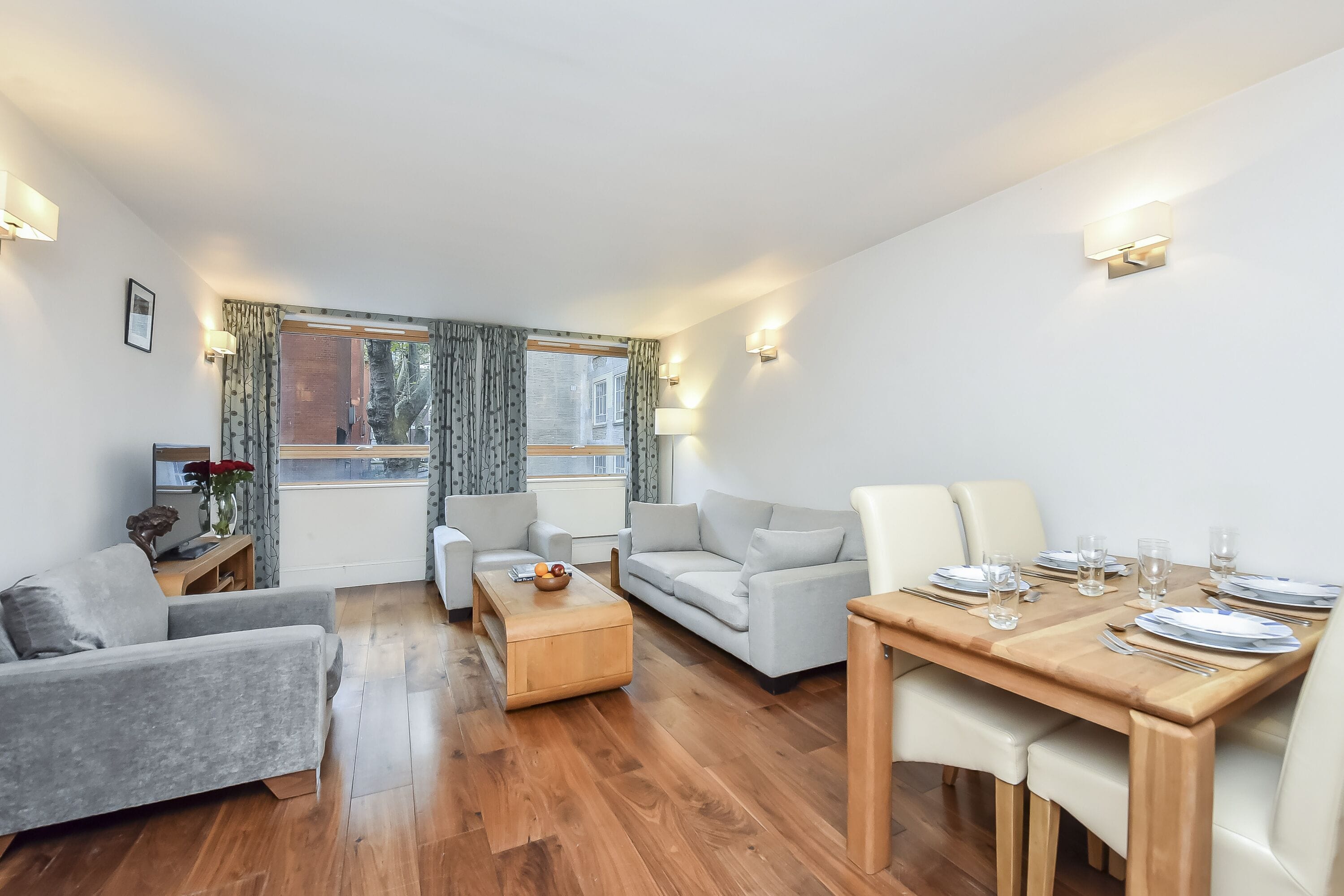 A modern living room with a sofa, coffee table, and dining table set for four.