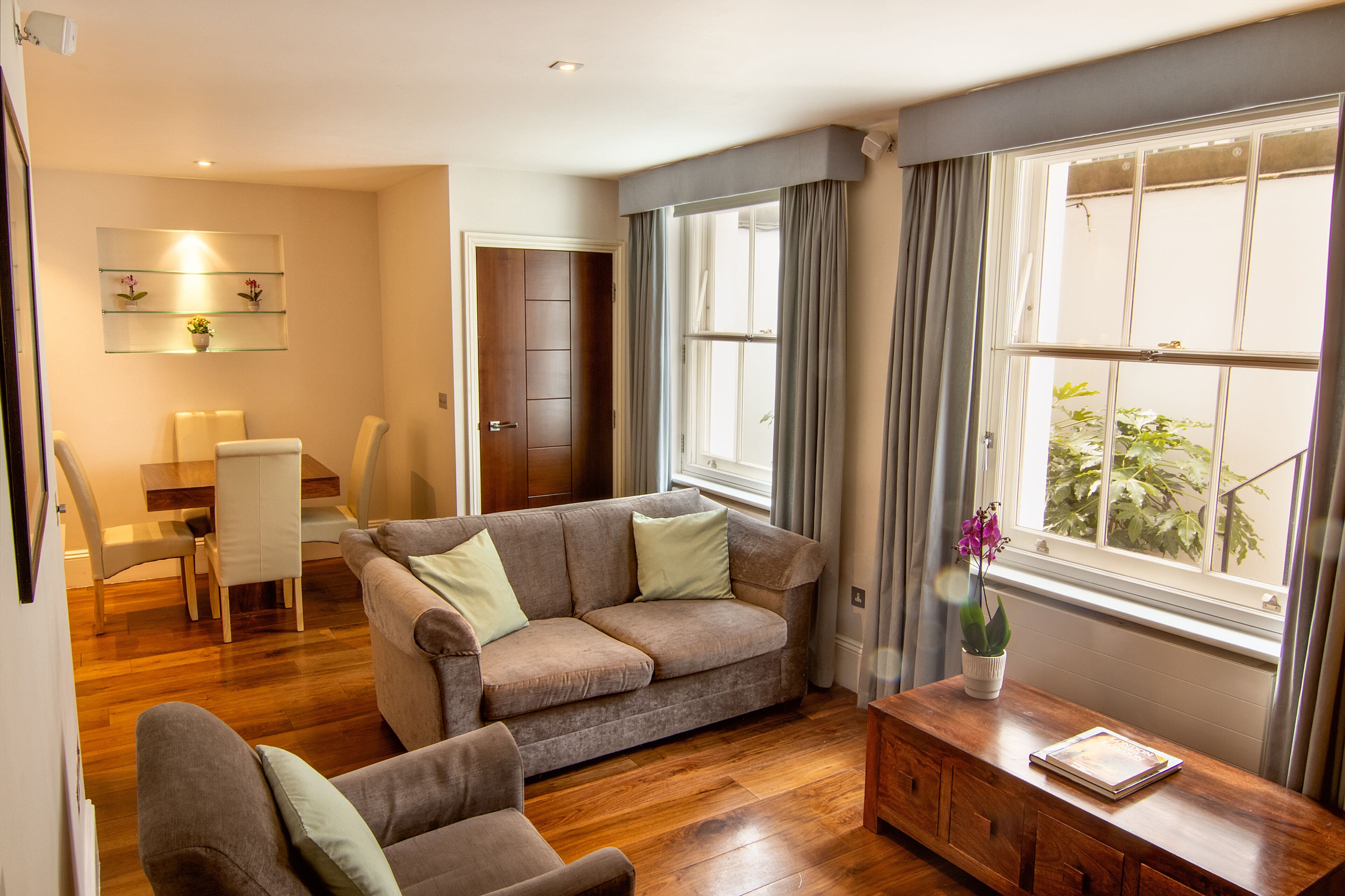 A living room with a sofa, armchair, wooden coffee table, and a dining area with a table and chairs.