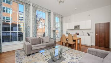 Uma sala de estar moderna com uma mesa de centro de vidro, um sofá e um espaço de jantar com uma mesa e cadeiras de madeira.