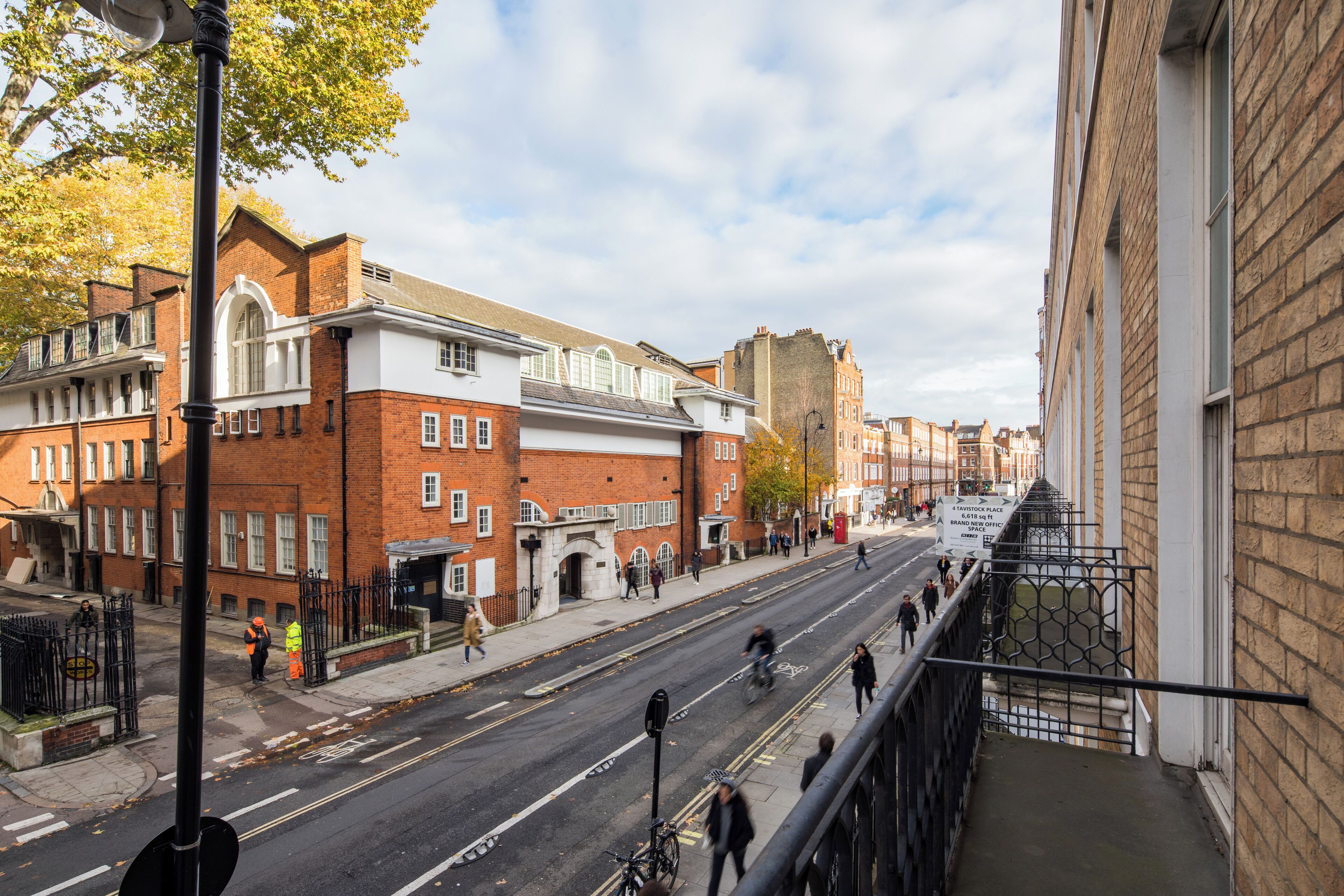 Une vue de rue avec des bâtiments, une piste cyclable et des piétons.