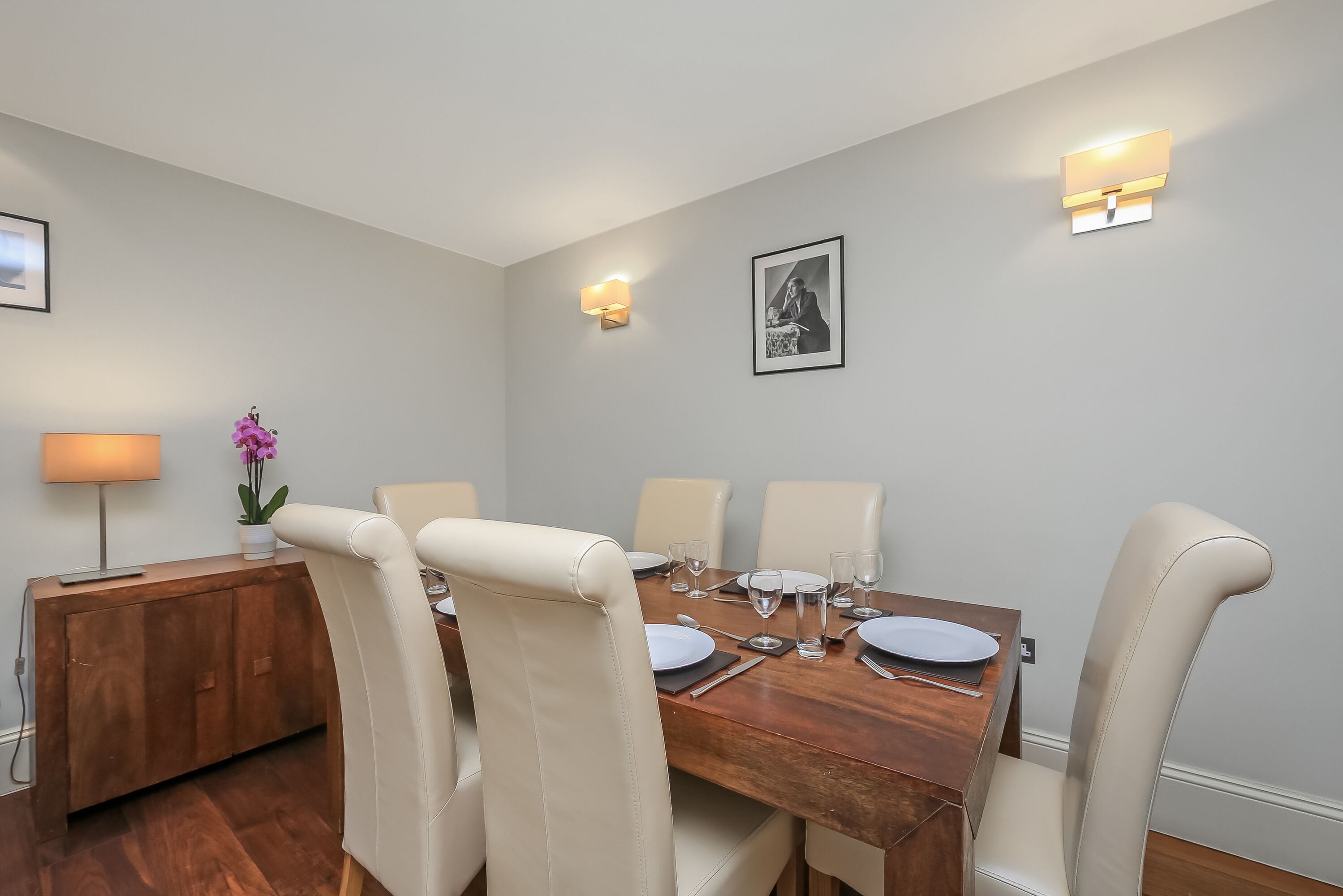 A dining area with a wooden table set for four, surrounded by beige chairs.