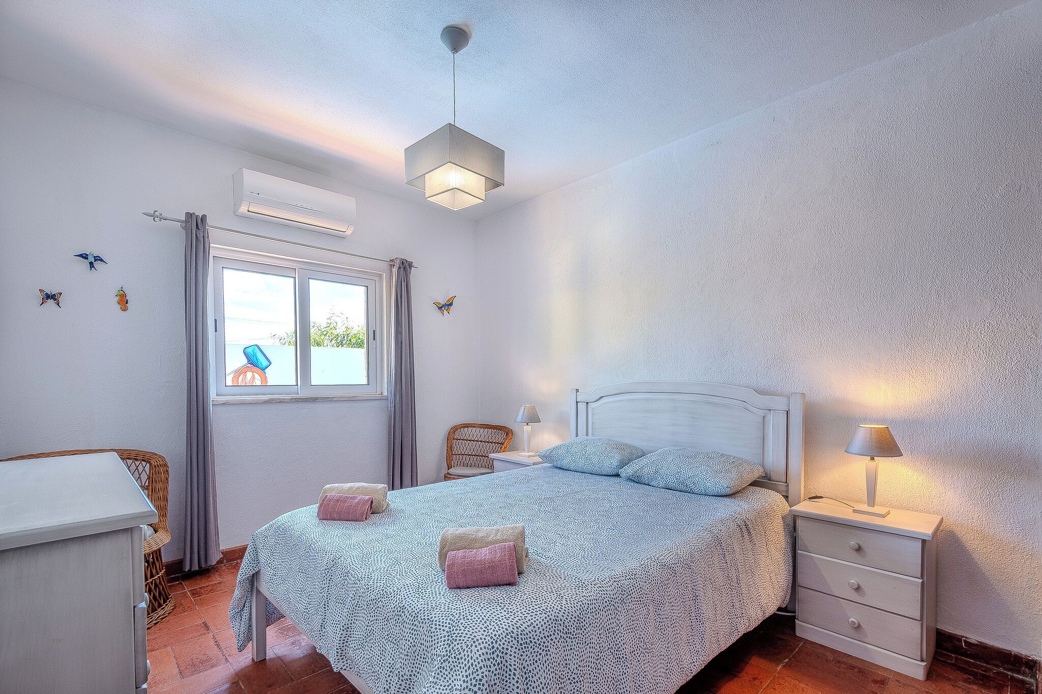 A bedroom with a bed, bedside table, and a window with curtains.