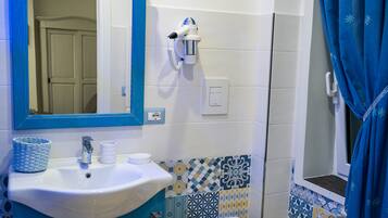 Ein Badezimmer mit einem weißen Waschbecken, blauen und weißen Fliesen mit Muster, einem blauen Vorhang und einem Spiegel mit blauem Rahmen.