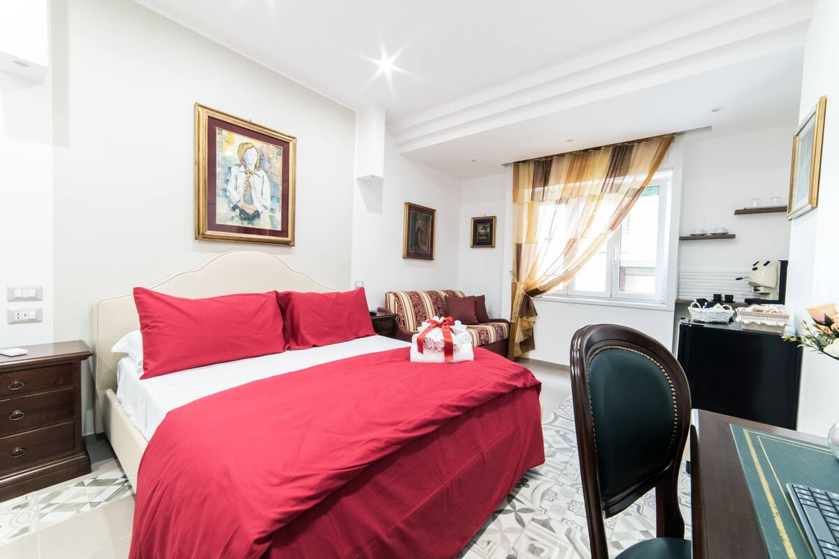 A bedroom with a large bed, a desk, and a chair.