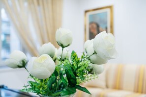 Un ramo de flores blancas en un florero de vidrio transparente sobre una mesa.