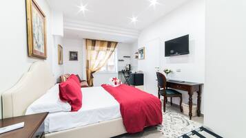 A hotel room with a bed, a desk, a chair, a television, and a window with curtains.