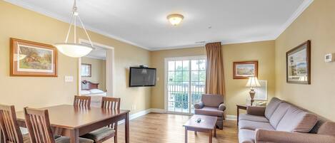 A living room with a dining table, chairs, a sofa, and a TV.