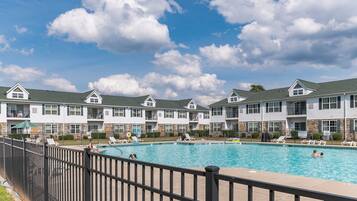 A swimming pool area with multiple lounge chairs and a fenced pool.