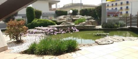 A courtyard with a small pond, stone steps, and some greenery.