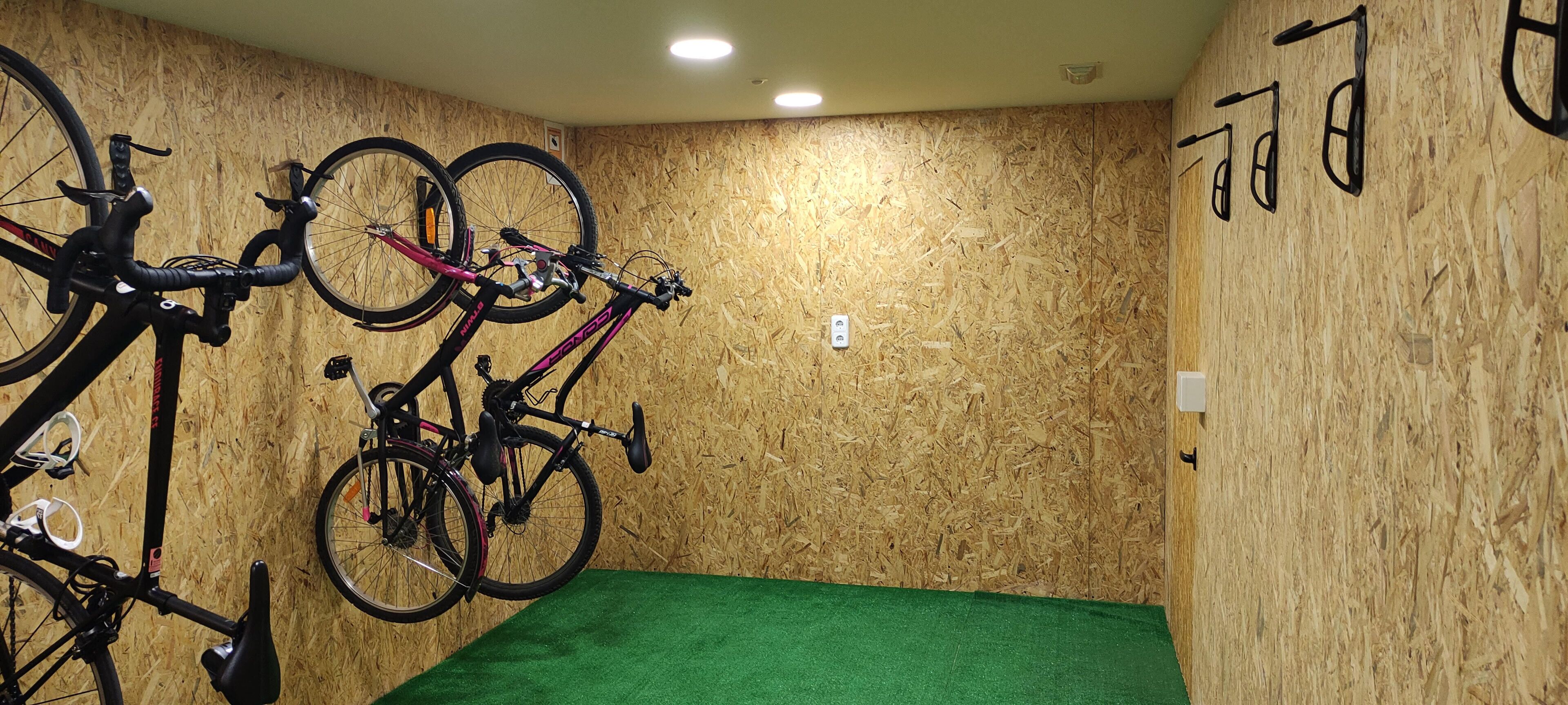 A room with wooden walls, a green carpet, and bicycles mounted on the wall.