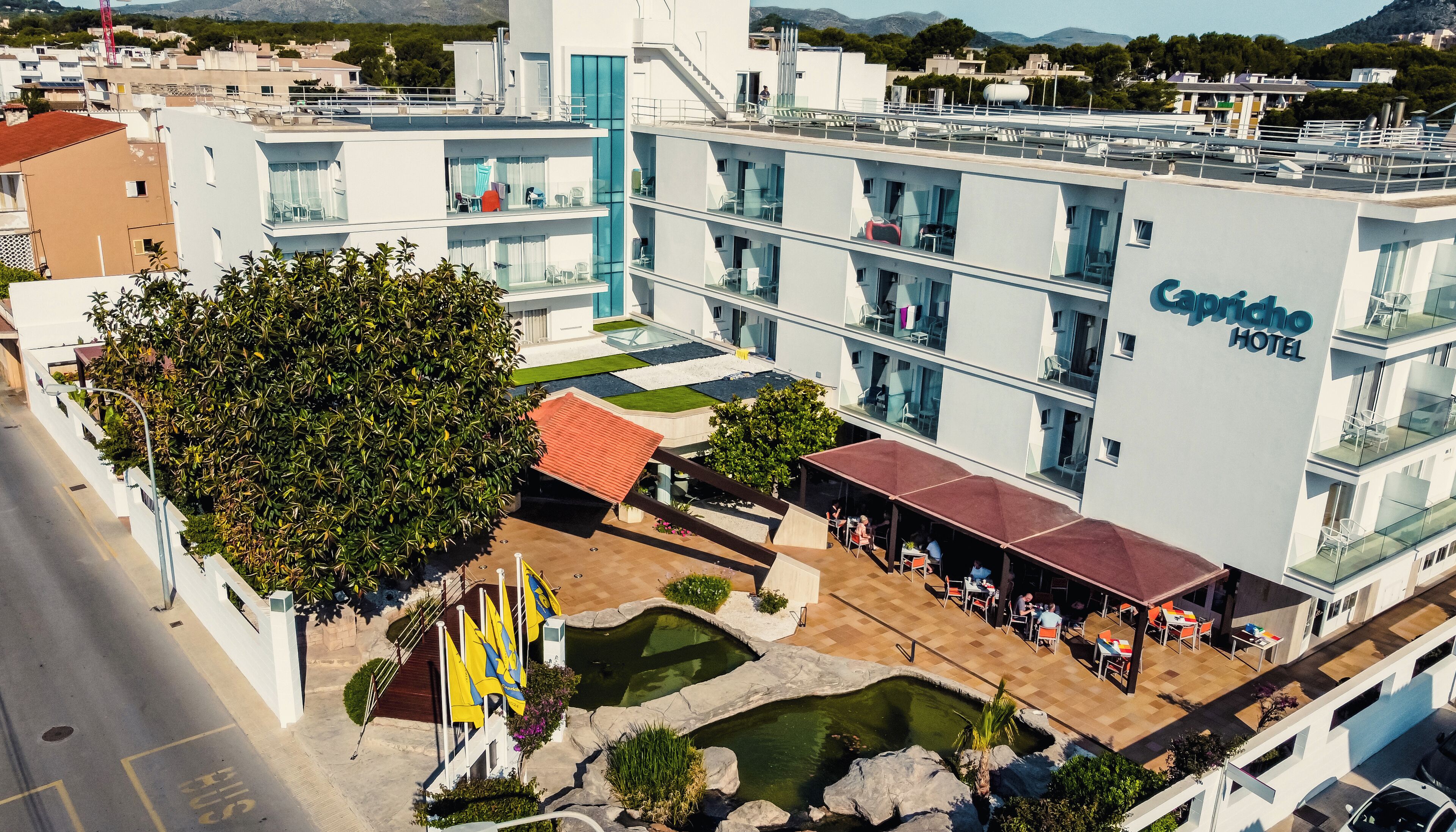 Un hotel con terraza en la azotea, mobiliario exterior y zona de piscina.
