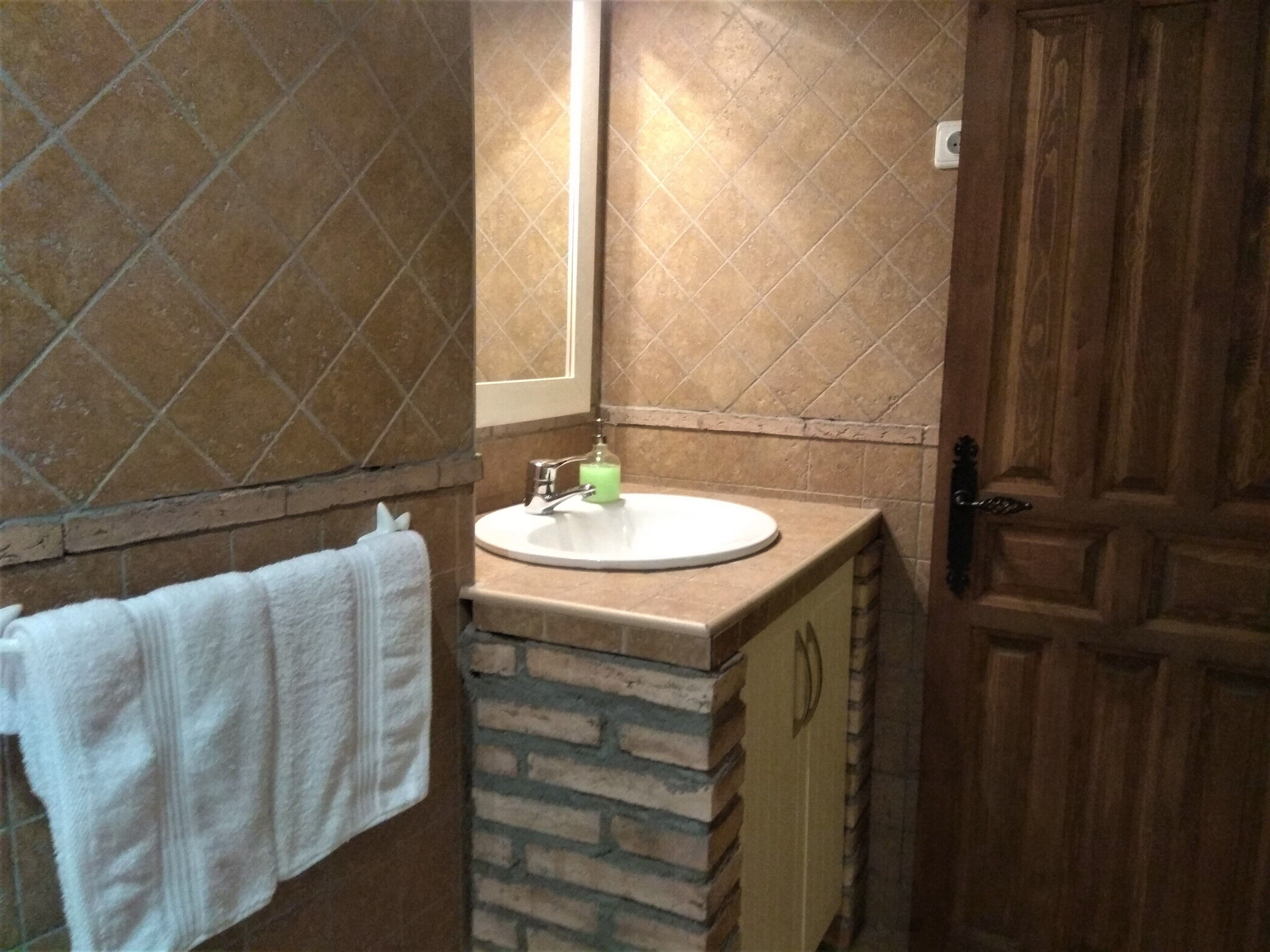 A bathroom with a white sink, a towel rack with a white towel, and a wooden door.
