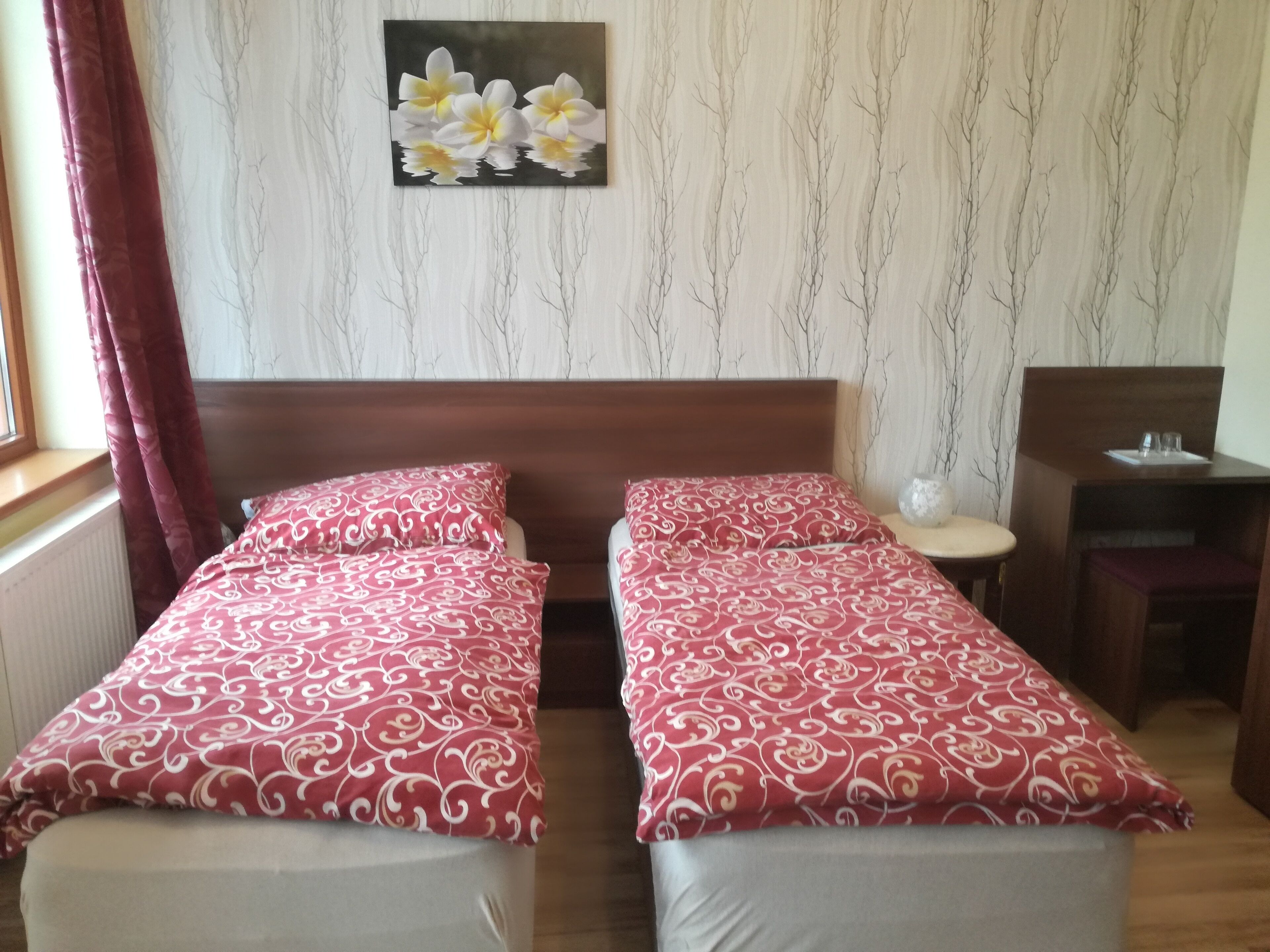 Een hotelkamer met twee bedden, een houten hoofdeinde, een tafeltje en een aan de muur hangend schilderij.