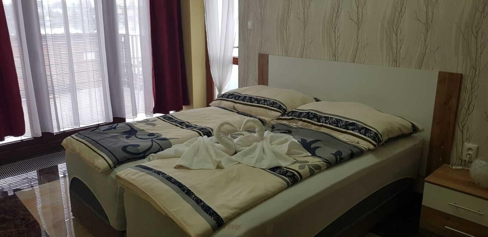 A hotel room with a bed, curtains, and a nightstand.