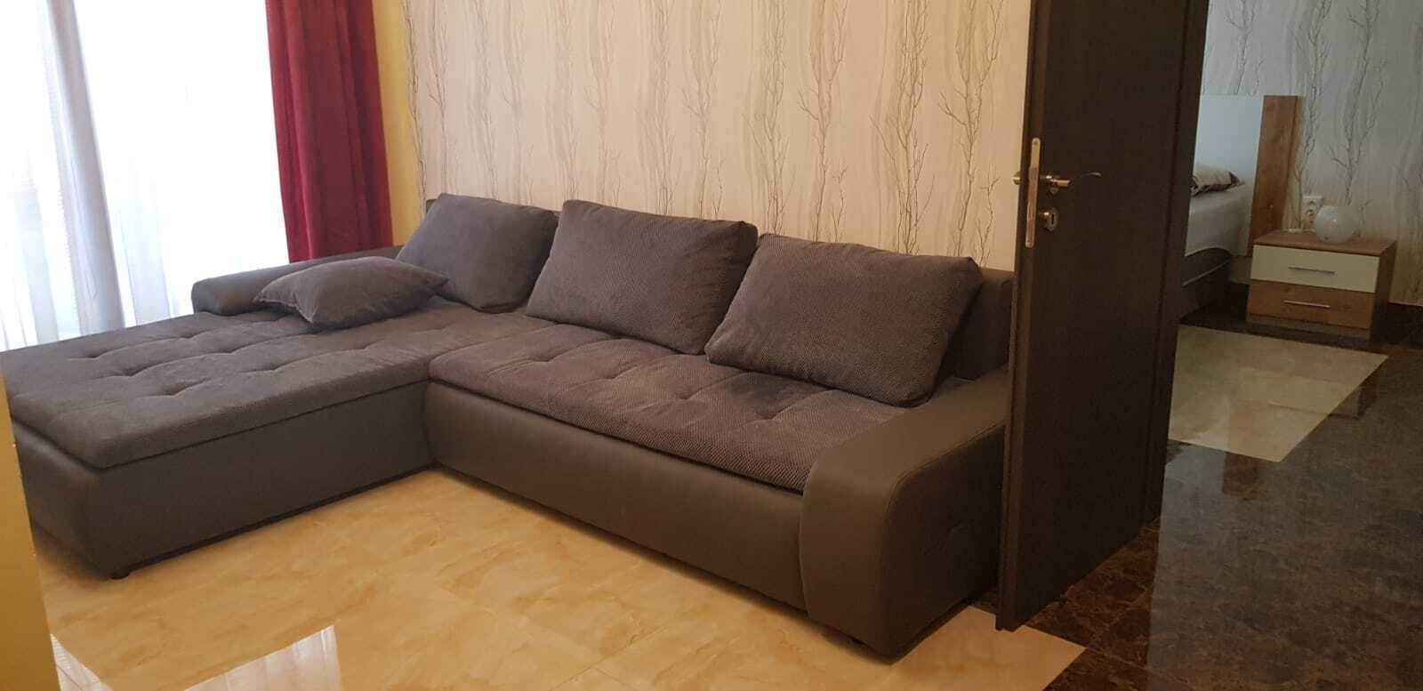 Una sala de estar moderna con un sofá modular, un mueble de madera y piso de mármol.