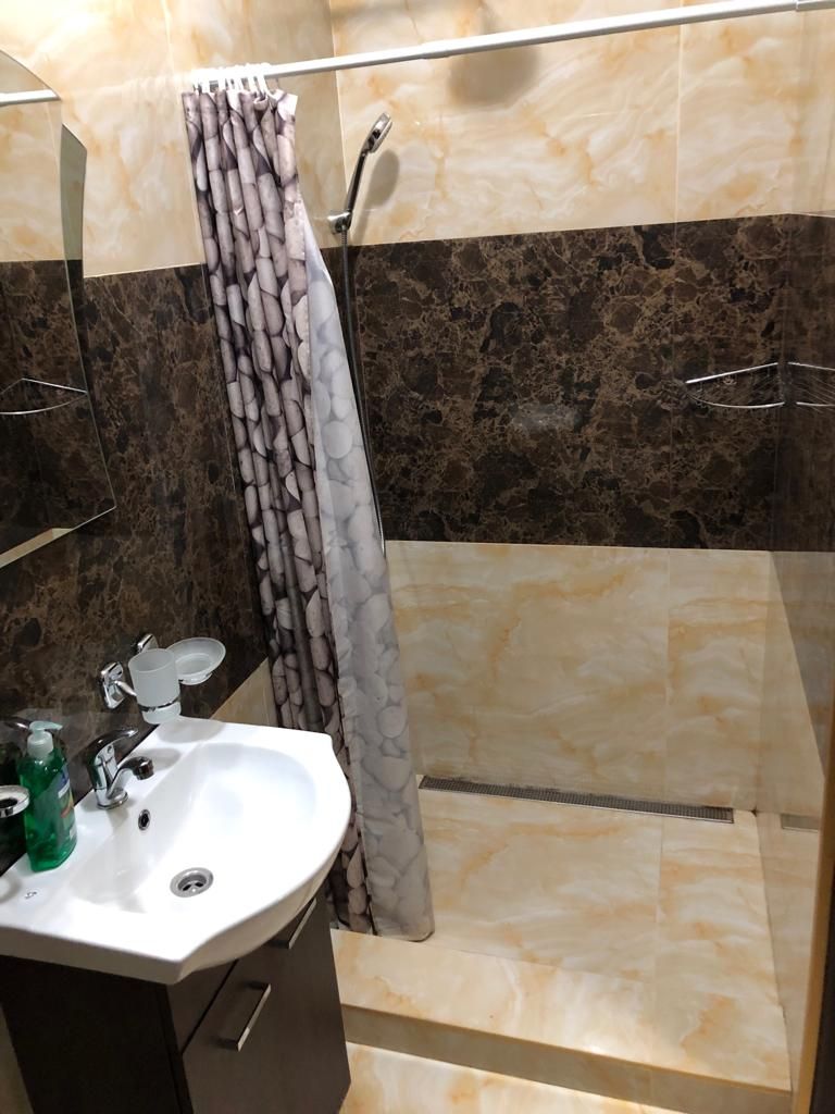 A bathroom with a shower, a sink with a mirror, and toiletries.
