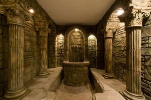 A stone-walled room with columns and a central stone structure. - Apartmanovy wellness garni hotel relax (Senec)