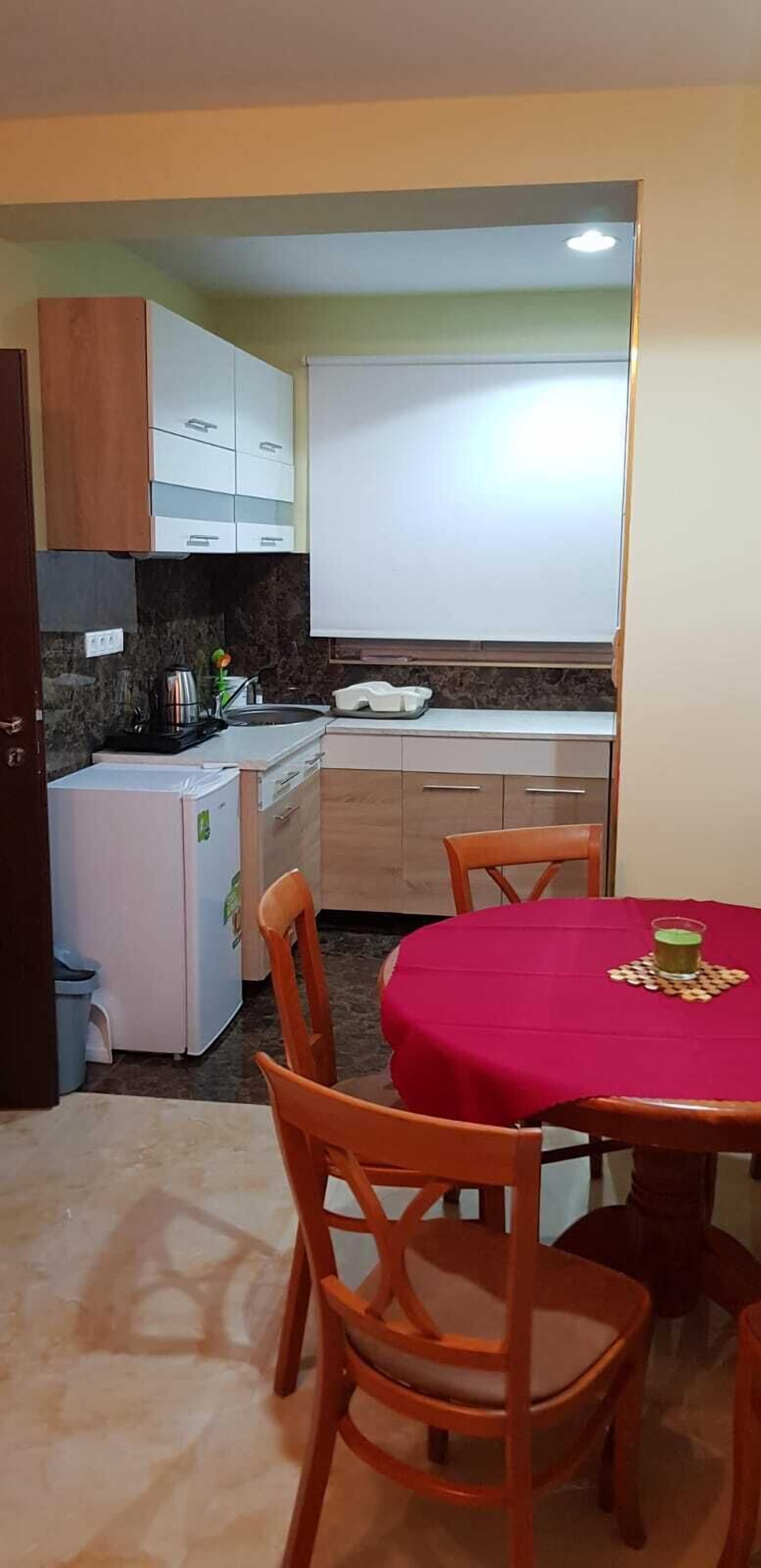 A compact kitchen with a dining area, featuring cabinets, a refrigerator, and a table with chairs.