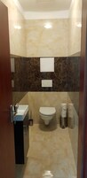 Un baño con inodoro, lavamanos y dos botes de basura.