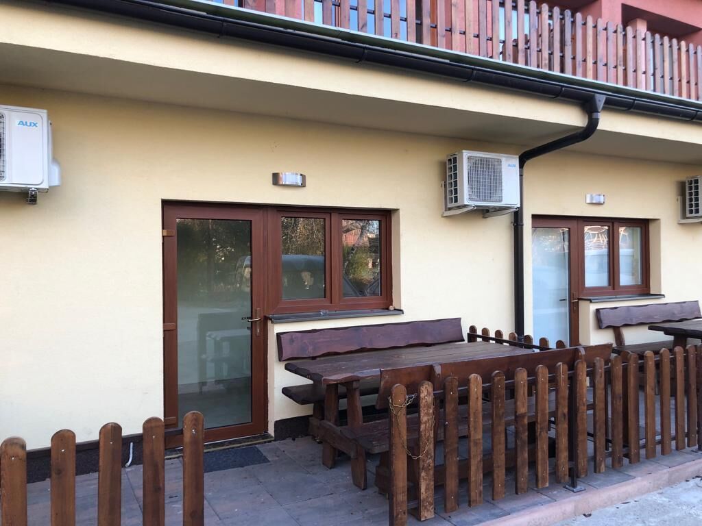 A building with a wooden fence, a bench, and two air conditioning units.